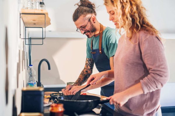 A man and a woman at a sink preparing food together