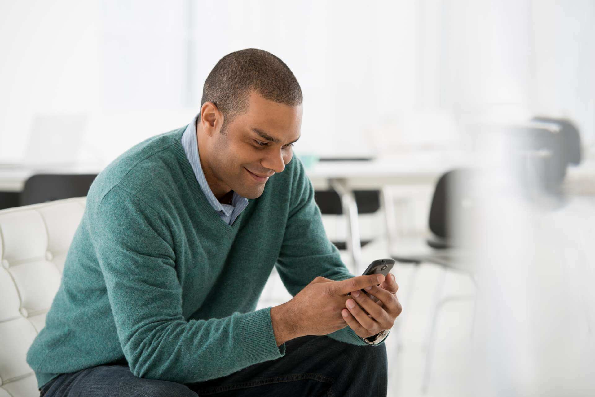 A man on a sofa looking at his mobile phone