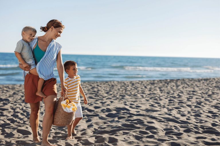 Family holiday on the beach. Mum walking with children