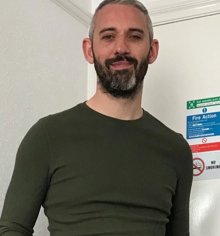 middle aged man in a dark green top smiling at the camera