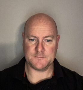 middle aged man taking a selfie in a black shirt