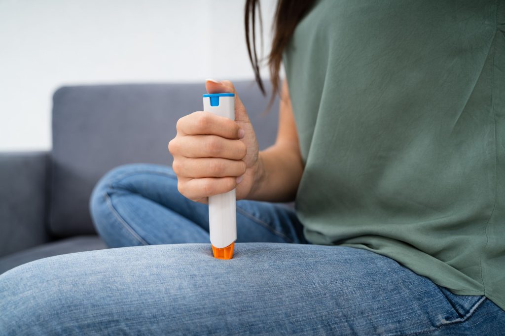 Woman injecting EpiPen in her leg