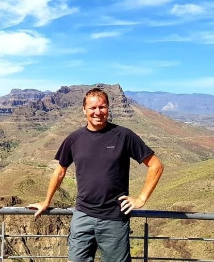 man posing for a picture with a landscape in the background