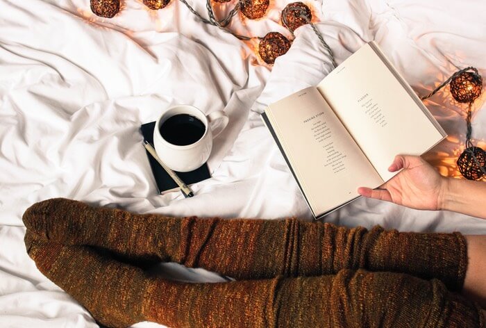 reading book with drink on bed