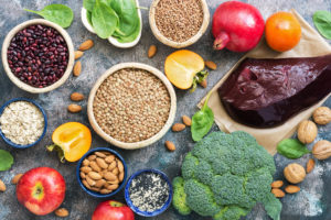 A variety of vegetables, nuts, fruit and a piece of liver on a grey tabletop