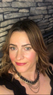 Grown up woman with highlights in her hair and a black top with necklace smiling at the camera