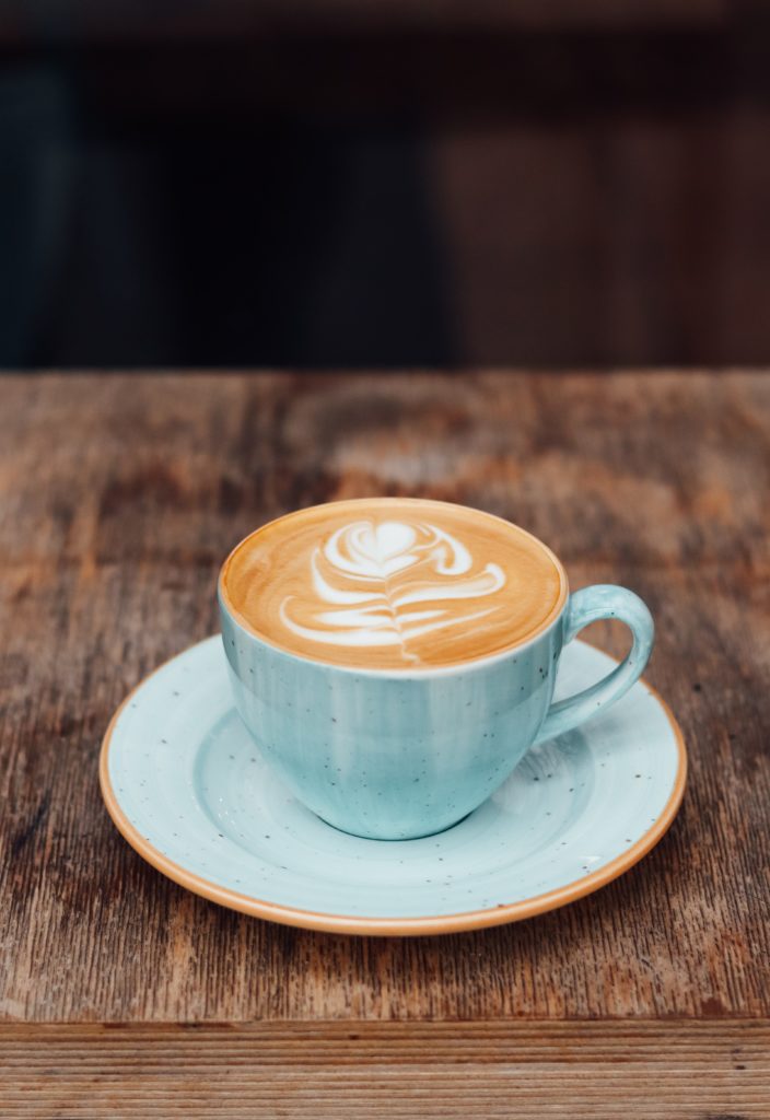 a cup of coffee on a wooden table with a dark background