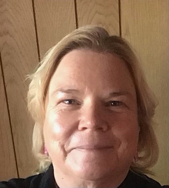 A close up shot of a blond woman looking at the camera and smiling