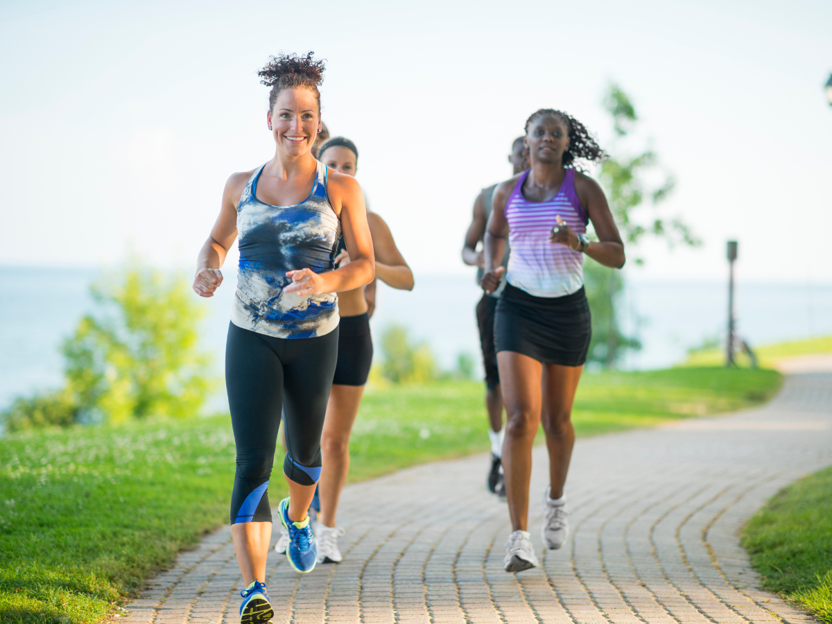 Women running on a path with the sea in the background