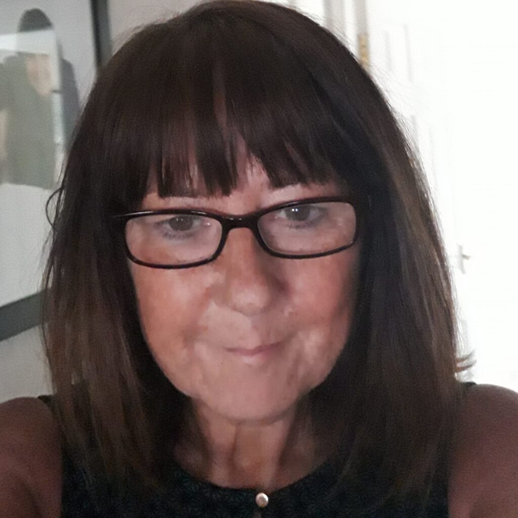 middle aged woman with glasses taking a selfie.