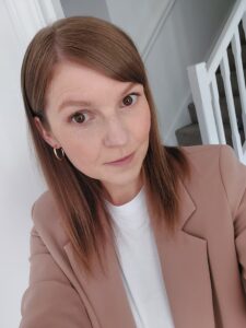 woman in a cream jacket posing for a selfie