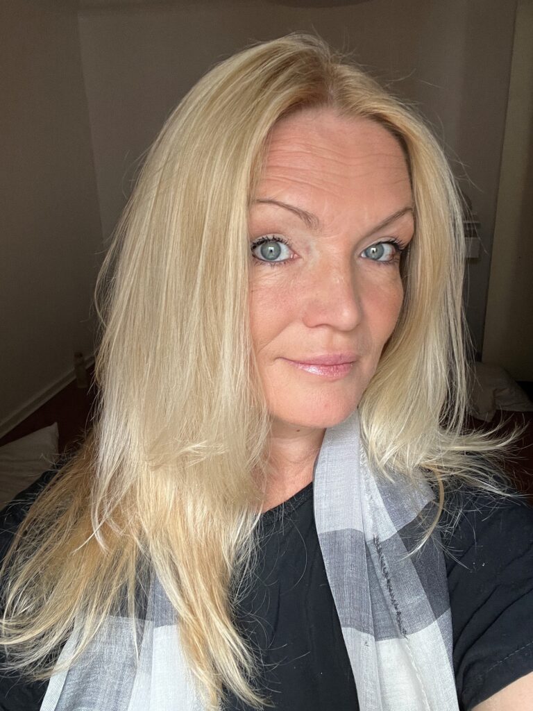 blond, middle aged woman with a scarf posing for a selfie