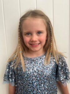 4 year old girl smiling at the camera in a glittery dress