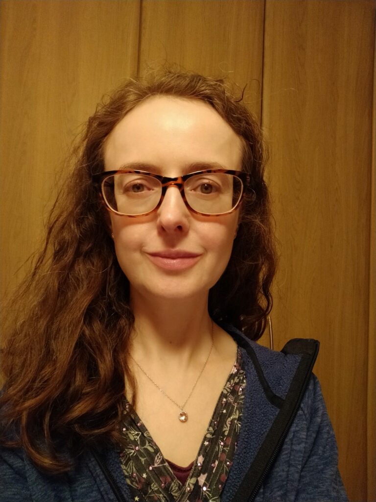 Young woman with long hair wearing glasses and posing for a selfie