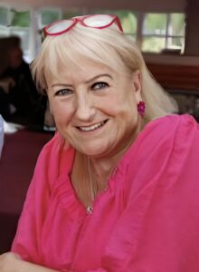 older female in a pink top smiling at the camera