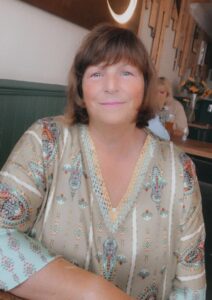 middle aged woman posing for the camera in a restaurant and wearing a cream top